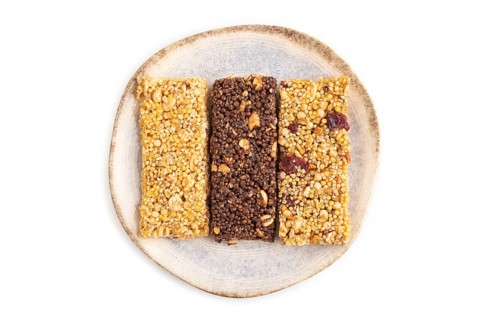 Granola bars with caramel, nuts, flakes in ceramic plate isolated on white background. Top view,