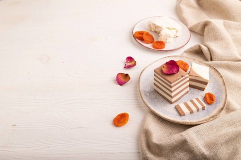 Cocoa and milk jelly with dried apricots on white wooden background and linen textile, side view,