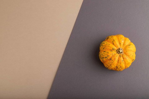 Orange Pumpkin on beige and gray pastel paper background. Top view, copy space, flat lay. healthy