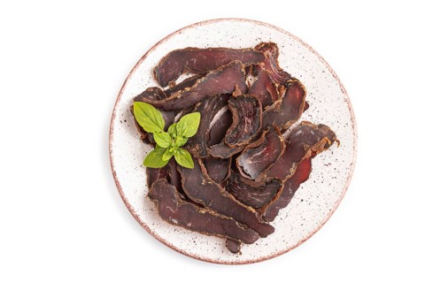 Armenian Basturma dried meat on plate with pepper and herbs isolated on white background. Top view,