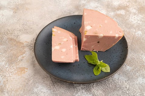 Mortadella sausage on wooden cutting board with pepper and herbs on brown concrete background. Side