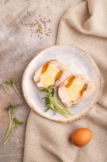 Chicken, egg and dried apricot meatloaf, microgreen on brown concrete background and linen textile.