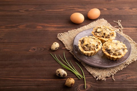 Tartlets with meat and cheese on brown wooden background and linen textile. side view, copy space