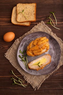 Chicken Schnitzel on gray plate with microgreen on brown wooden background and linen textile. top