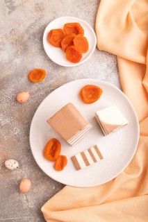 Cocoa and milk jelly with dried apricots on brown concrete background and orange textile, top view,