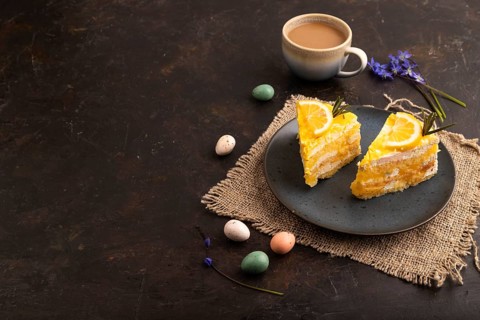 Lemon cake on black concrete background and linen textile, cup of coffee, side view, Copy space