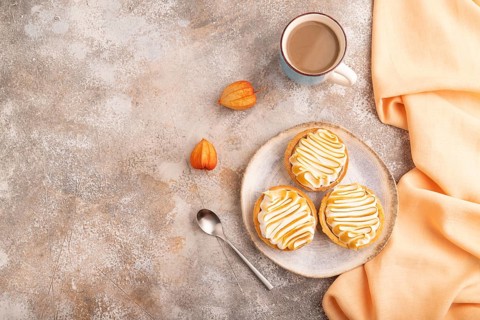 French lemon tart with meringue on brown concrete background, cup of coffee, orange linen textile,
