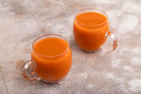 Two glasses with carrot juice, on brown concrete background. Diet, healthy eating concept. side