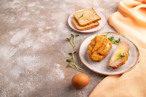 Chicken Schnitzel on blue plate with microgreen on brown concrete background and orange linen
