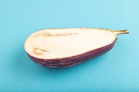 Purple Cutted eggplant with white stripes on blue pastel background. Side view, copy space.