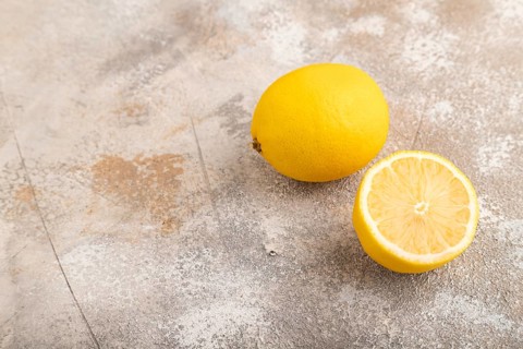 Yellow Lemon Cut in half on brown concrete background. Side view, copy space. healthy food,