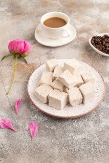 Coffee marshmallow with cup of coffee on brown concrete background. side view, close up