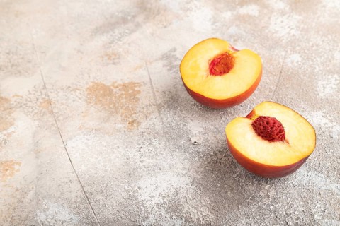 Peach Cut in half on brown concrete background. Side view, copy space. healthy food, vegetable,