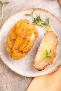 Chicken Schnitzel on blue plate with microgreen on brown concrete background and orange linen