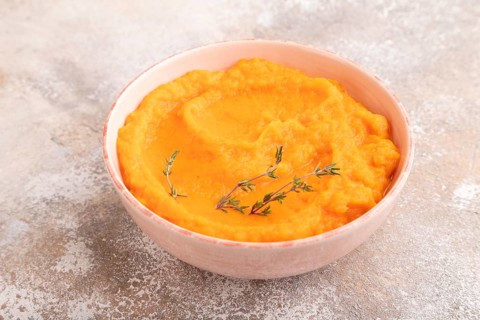 Sweet potato porridge in ceramic bowl on brown concrete background. Diet, healthy eating concept.