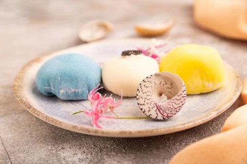 Japanese Mochi Cakes on brown concrete background and orange textile, side view, close up,