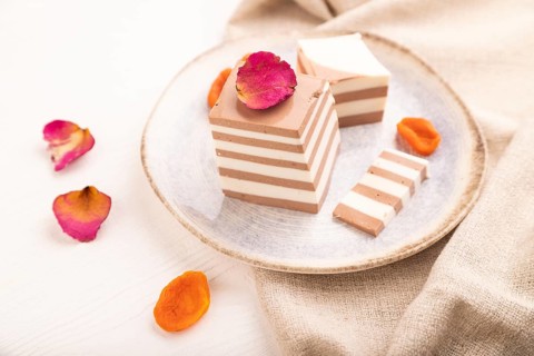 Cocoa and milk jelly with dried apricots on white wooden background and linen textile, side view,