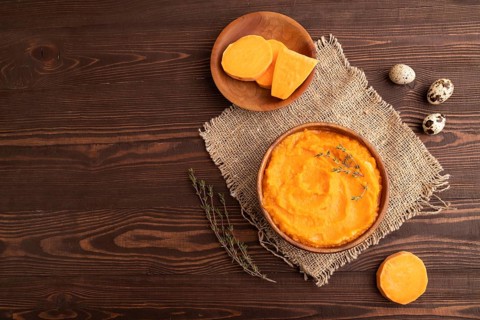 Sweet potato porridge in wooden bowl on wooden background and linen textile. Diet, healthy eating