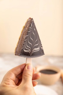 Chocolate and Vanilla Cake pops Marshmallow with hand with cup of coffee on brown concrete
