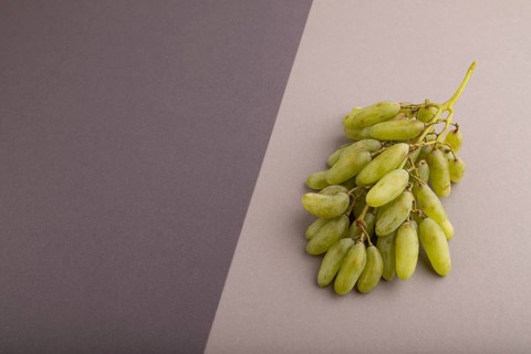 Green grapes on gray and black paper pastel background. Side view, copy space. healthy food,