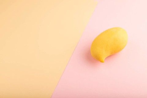 Orange mango on orange and pink paper pastel background. Side view, copy space. healthy food,