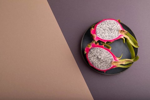 Ripe Pitaya on blue plate on brown and beige pastel paper background, top view, flat lay, copy