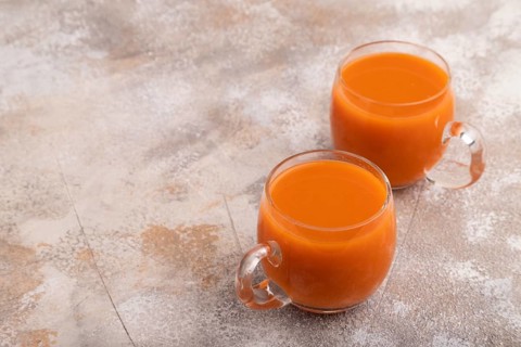 Two glasses with carrot juice, on brown concrete background. Diet, healthy eating concept. side