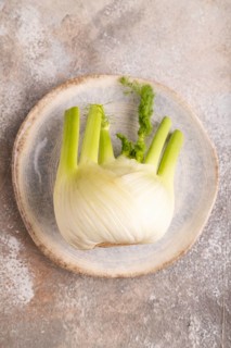 Fresh Fennel bulb on blue plate on brown concrete background, top view, flat lay, copy space,