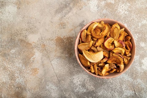 Dried Apples in ceramic bowl on brown concrete background. Top view, copy space, flat lay. healthy