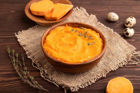 Sweet potato porridge in wooden bowl on wooden background and linen textile. Diet, healthy eating