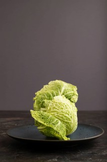 Green lettuce on blue plate on black concrete background. Side view, copy space. healthy food,
