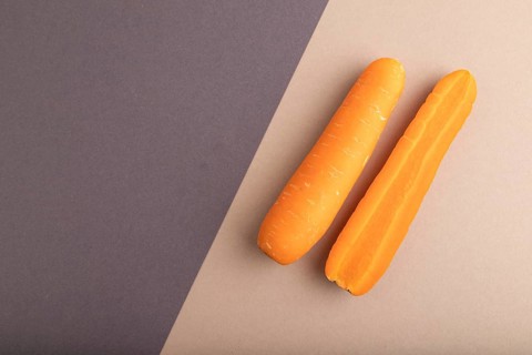Orange Carrot on beige and gray pastel paper background. Top view, copy space, flat lay. healthy