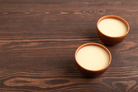 Organic non dairy banana and soy milk in clay cup on brown wooden background. Vegan healthy food