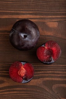 Purple Plum Cut in half on brown wooden background. Top view, flat lay, close up. healthy food,