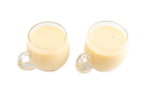 Organic non dairy banana and soy milk in glass cup on brown wooden background. Vegan healthy food