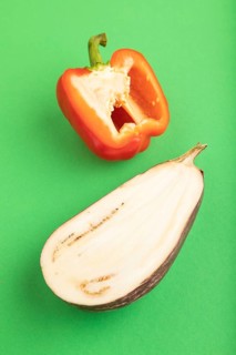 Red Cutted pepper and Purple Cutted eggplant on green pastel background. Side view, copy space.