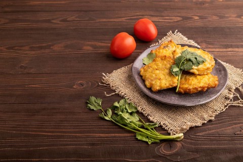 Fried crispy Chicken pancakes on brown wooden background and linen textile. side view, copy space