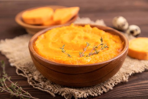 Sweet potato porridge in wooden bowl on wooden background and linen textile. Diet, healthy eating