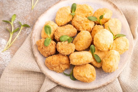 Fried crispy Chicken Nuggets with ketchup, microgreen on brown concrete background and linen