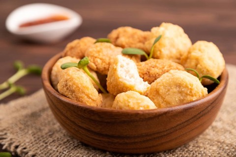 Fried crispy Chicken Nuggets with ketchup, microgreen on brown wooden background and linen textile.