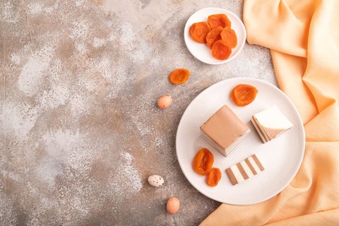 Cocoa and milk jelly with dried apricots on brown concrete background and orange textile, top view,