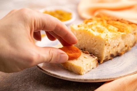 ?ottage cheese ?asserole, Curd cake, with dried apricots and raisins with hand on brown concrete