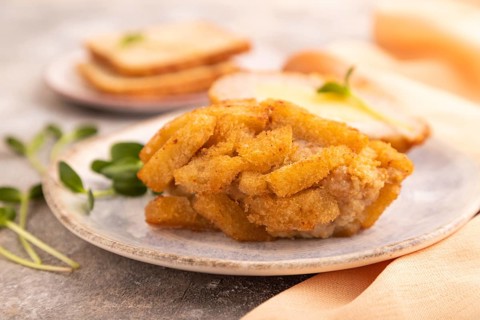 Chicken Schnitzel on blue plate with microgreen on brown concrete background and orange linen