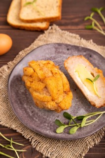 Chicken Schnitzel on gray plate with microgreen on brown wooden background and linen textile. side