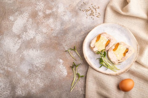 Chicken, egg and dried apricot meatloaf, microgreen on brown concrete background and linen textile.