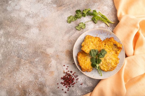 Fried crispy Chicken pancakes on brown concrete background and orange linen textile. top view, flat
