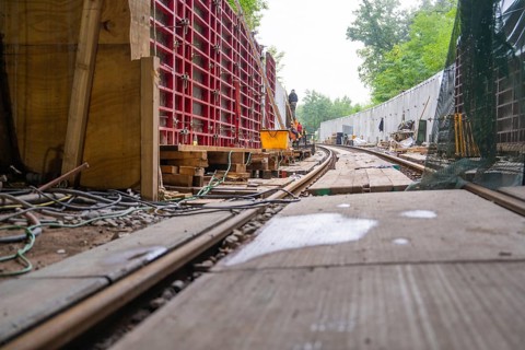 Baustelle mit Schienen und Holzbrettern in einem Waldgebiet, von Kabeln und Konstruktionsmaterial