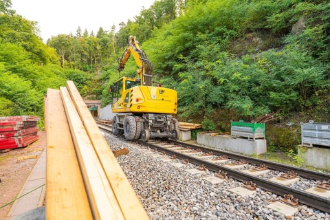 Baufahrzeug mit Kran auf Schienen in einer bewaldeten Baustelle, Bau der Hermann Hessenahn, Calw,