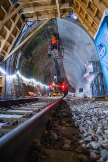 Tunnelbau mit Schienen, Maschinen, beleuchteter Atmosphäre und einem Bauarbeiter in Aktion, Bau der
