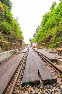 Eisenbahnschienen mit Holzplanken in einer eingefassten, grünen Bauumgebung, Bau der Hermann